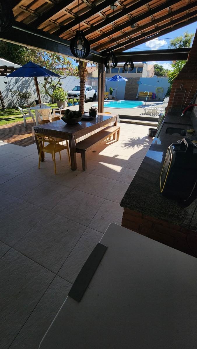 Área coberta com mesa de jantar, churrasqueira e vista para a piscina