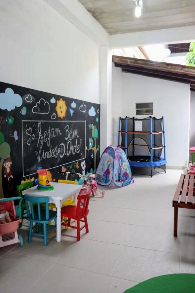 Área kids com brinquedos, cama elástica e lousa de boas-vindas