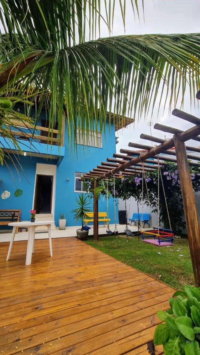 Deck de madeira com pergolado e balanço em frente à casa