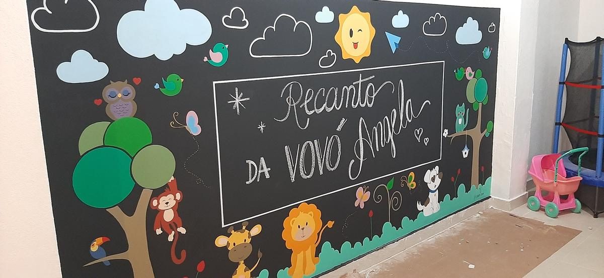 Mural pintado com bichinhos e a frase Recanto da Vovó Angela na área kids