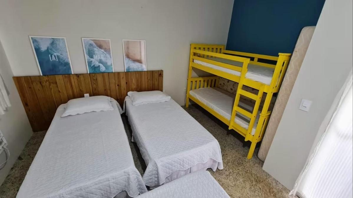 Quarto com três camas de solteiro e um beliche amarelo