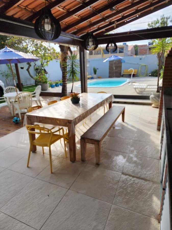 Varanda coberta com mesa grande e vista para a piscina